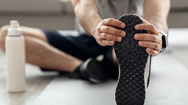 A man sitting on the floor stretching his hamstrings